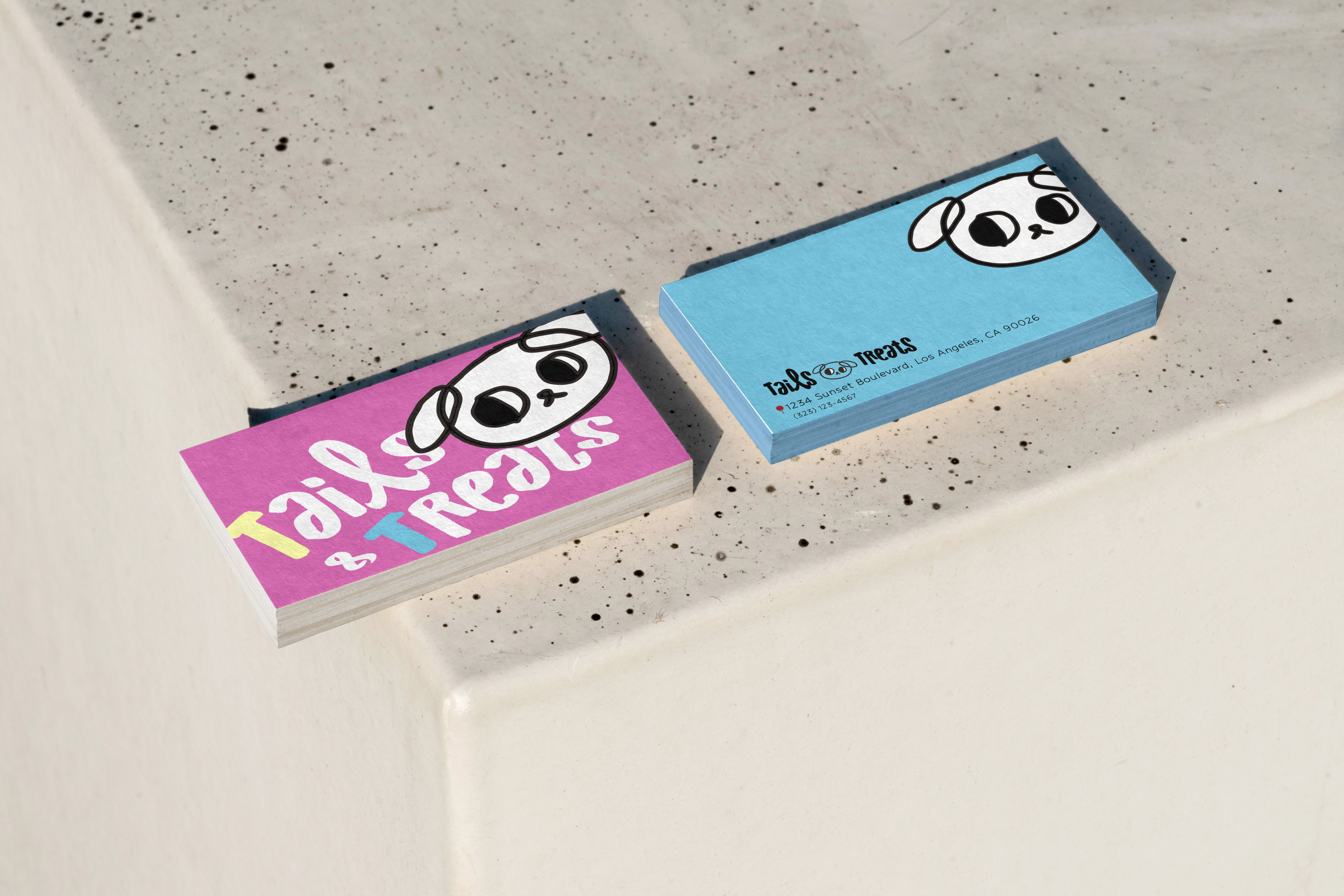 Tails and Treats business cards on a stone ledge